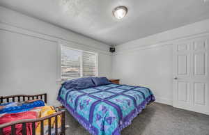 Carpeted bedroom featuring a textured ceiling and baseboards