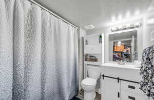 Full bathroom featuring a textured ceiling and vanity