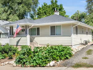 View of front of house featuring a shingled roof and a chimney