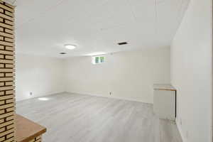 Basement featuring light wood-style vinyl flooring.