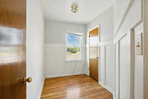 Potential office space with decorative, wainscoting, and wood flooring.