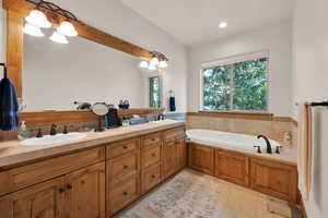 Bathroom featuring double vanity, a garden tub, tile patterned floors, recessed lighting, and a chandelier