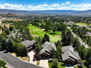 Aerial view of residential area with a mountain backdrop and a golf club