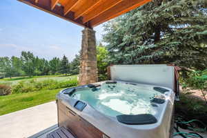 View of patio / terrace with a hot tub, view of scattered trees, and view of golf course