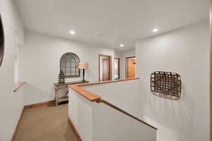 Corridor with recessed lighting, light colored carpet, and an upstairs landing