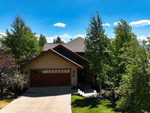 View of front of property featuring stone siding, driveway, stucco siding, a garage, and a shingled roof