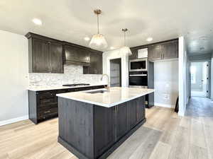 Kitchen featuring light countertops, backsplash, stainless steel appliances, light wood-style flooring, and recessed lighting