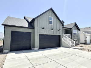 Modern inspired farmhouse with board and batten siding, roof with shingles, and driveway