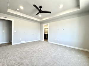 Unfurnished bedroom with recessed lighting, carpet floors, a raised ceiling, and ensuite bath