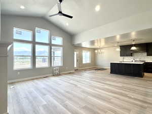 Unfurnished living room featuring ceiling fan, light wood-style floors, recessed lighting, high vaulted ceiling, and a textured ceiling