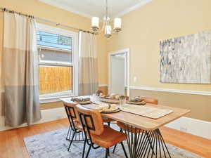 Dining space with crown molding, wood-type flooring, and a chandelier