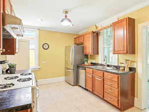 Kitchen featuring stainless steel appliances, crown molding, ventilation hood, marble countertops.