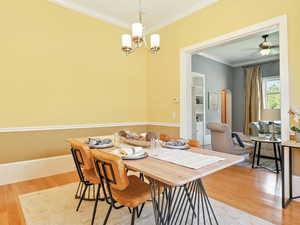 Dining space with crown molding, light wood-style flooring, a chandelier, and arched walkways