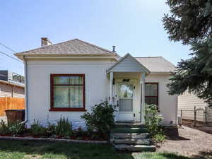 View of front of house featuring brick siding, a shingled roof, and a chimney