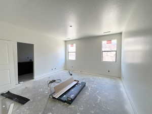 Empty room with a textured ceiling and baseboards