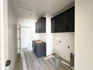 Laundry room with cabinet space, washer hookup, and light wood finished floors