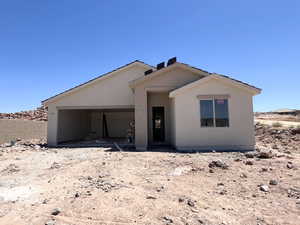 View of front of house featuring an attached garage and stucco siding