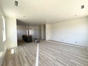 Unfurnished living room with light wood-type flooring and baseboards