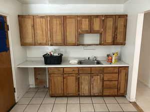 Kitchen featuring brown cabinetry, light countertops, light tile patterned floors, and open shelves