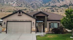 View of front of home with stone siding, an attached garage, a front lawn, and concrete driveway