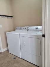 Laundry area with separate washer and dryer and tile patterned flooring