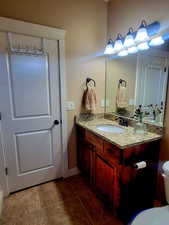 Bathroom featuring granite top vanity and toilet