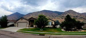 Ranch-style home with stone siding, concrete driveway, a mountain view, a front lawn, and a garage
