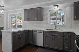 Kitchen with dark wood-type flooring, appliances with stainless steel finishes, crown molding, light stone counters, and a textured ceiling