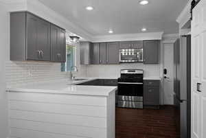 Kitchen featuring crown molding, a peninsula, a barn door, stainless steel appliances, and a textured ceiling