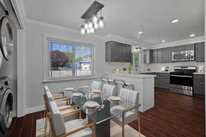 Kitchen featuring wood tiled floors, appliances with stainless steel finishes, crown molding, gray cabinets, and a textured ceiling
