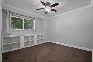 Spare room with dark colored carpet, ornamental molding, and a ceiling fan