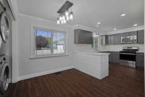 Kitchen featuring stainless steel appliances, ornamental molding, gray cabinets, a textured ceiling, and a peninsula
