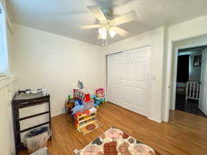 Bedroom with wood finished floors, ceiling fan, and a textured ceiling