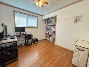 Office with a textured ceiling, crown molding, light wood finished floors, and ceiling fan