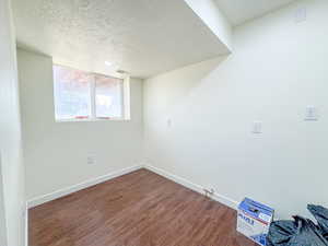 Basement featuring a textured ceiling and wood finished floors