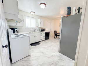 Kitchen with stainless steel appliances, light countertops, light marble finish flooring, custom exhaust hood, and a textured ceiling