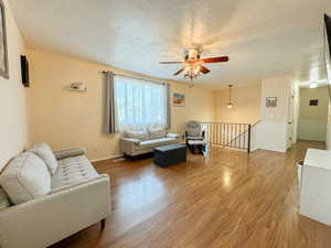 Spacious Living room featuring a textured ceiling, wood finished floors, and a ceiling fan