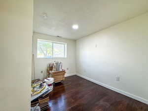 Empty room featuring a textured ceiling, dark wood-style floors, and recessed lighting