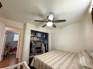 Bedroom with a closet, wood finished floors, a ceiling fan, and a textured ceiling