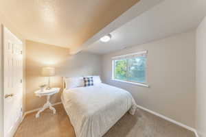 Bedroom featuring a textured ceiling, carpet floors, and beam ceiling