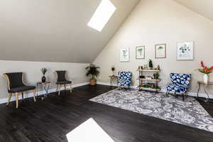 Living area featuring a skylight, vaulted ceiling, and wood finished floors