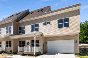 View of front facade featuring covered porch, an attached garage, driveway, and a shingled roof