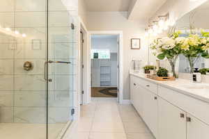 Bathroom featuring a marble finish shower, vanity, marble finish flooring, and a spacious closet