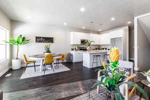 Kitchen with a kitchen island with sink, light countertops, white cabinets, dark wood finished floors, and recessed lighting