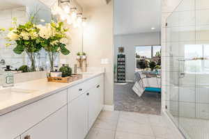 Ensuite bathroom featuring double vanity, marble finish floors, a stall shower, and recessed lighting