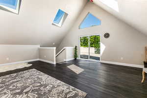 Additional living space with a skylight, wood finished floors, and high vaulted ceiling