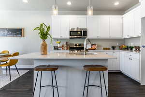Kitchen featuring appliances with stainless steel finishes, dark wood-type flooring, a breakfast bar area, recessed lighting, and a textured ceiling