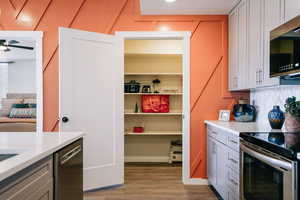 Kitchen with light countertops, appliances with stainless steel finishes, light wood-style flooring, and gray cabinets