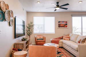 Living room featuring plenty of natural light, a ceiling fan, a textured ceiling, and recessed lighting