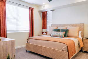 Bedroom with carpet floors, multiple windows, and a ceiling fan